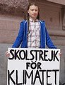 Greta Thunberg segurando uma placa de protesto escrita "Greves escolares pelo clima".